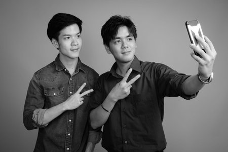 Two young handsome Asian men against gray background