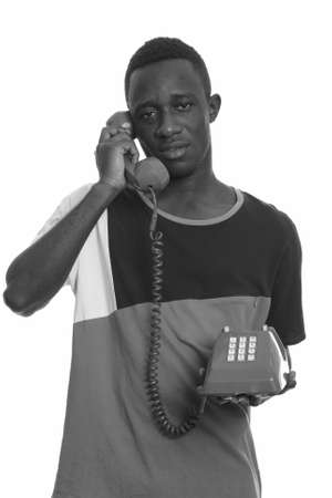 Young African man talking on old telephone looking tiredの写真素材