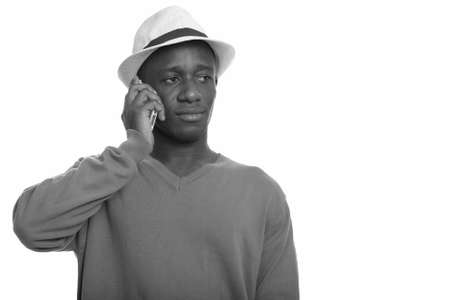Young handsome African man talking on mobile phone while thinkingの写真素材