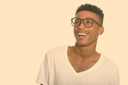Portrait of happy young handsome African man with afro hair thinking