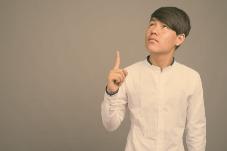 Young Asian teenage boy against gray backgroundの写真素材
