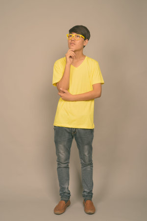 Young Asian teenage boy against gray backgroundの写真素材