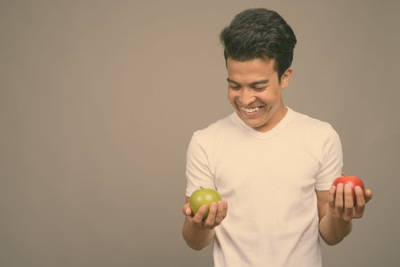 Portrait of young Asian man against gray background