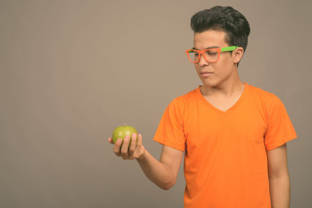 Portrait of young Asian man against gray background