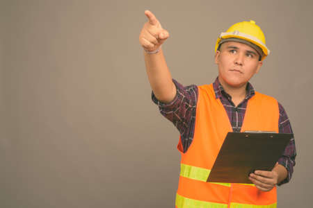 Young Asian man construction worker against gray backgroundの写真素材