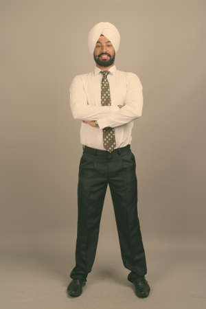 Young handsome Indian Sikh businessman wearing turban against gray backgroundの写真素材