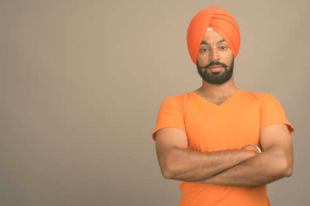 Young handsome Indian Sikh man wearing turban against gray backgroundの写真素材