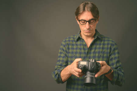 Mature handsome Italian man against gray backgroundの写真素材
