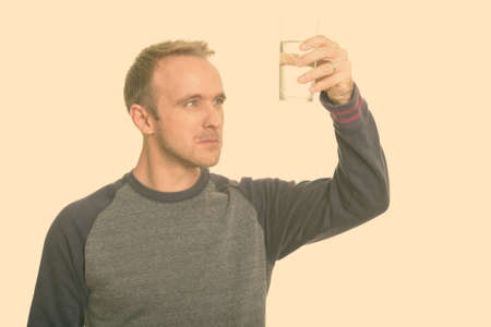 Handsome Caucasian man observing glass of water while thinkingの写真素材