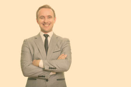 Happy handsome blond businessman in suit smiling with arms crossedの写真素材