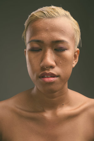 Young beautiful rebellious woman with short hair against gray background