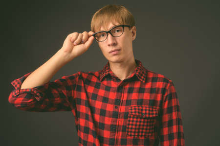 Young handsome man with blond hair against gray backgroundの写真素材