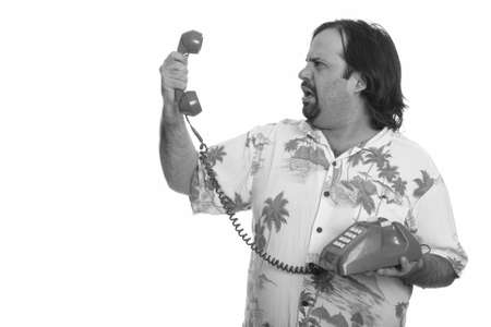 Profile view of fat Caucasian man holding old telephone looking angryの写真素材