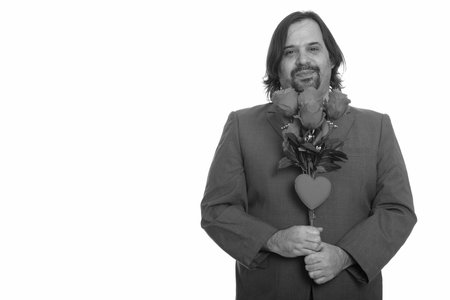 Happy fat Caucasian businessman smiling holding red roses and heart ready for Valentines day