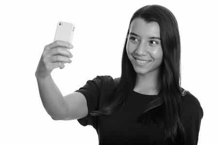 Young happy Caucasian woman smiling and taking selfie with mobile phone