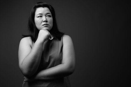 Beautiful overweight Asian woman against gray background
