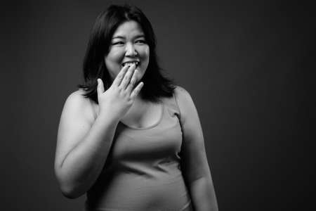 Beautiful overweight Asian woman against gray backgroundの写真素材