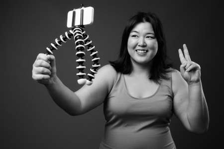 Beautiful overweight Asian woman against gray backgroundの写真素材