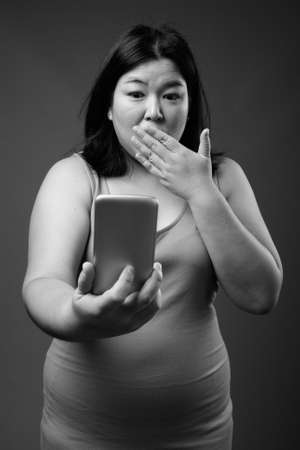 Beautiful overweight Asian woman against gray backgroundの写真素材