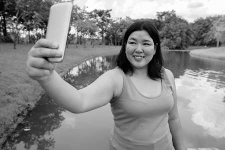 Beautiful overweight Asian woman relaxing at the park in the cityの写真素材
