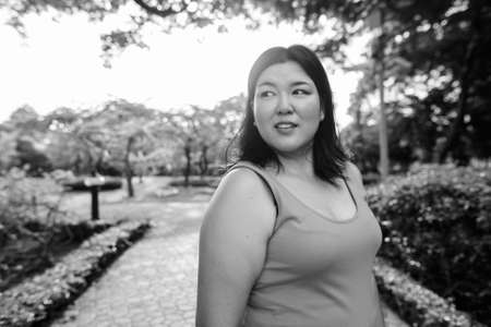 Beautiful overweight Asian woman relaxing at the park in the cityの写真素材