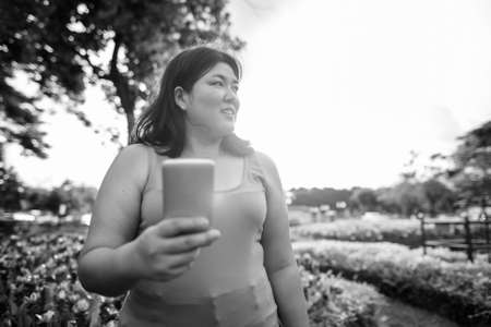 Beautiful overweight Asian woman relaxing at the park in the cityの写真素材