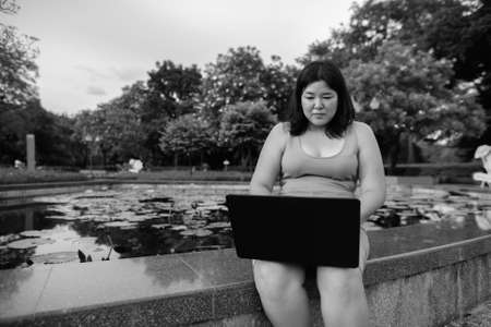 Beautiful overweight Asian woman relaxing at the park in the cityの写真素材