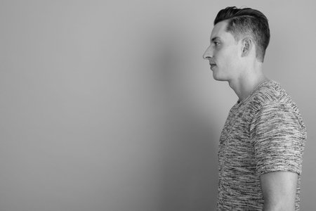 Young handsome man wearing gray shirt against gray background
