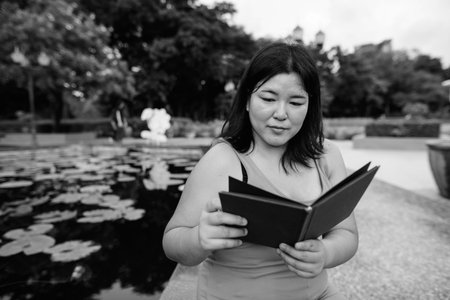 Beautiful overweight Asian woman relaxing at the park in the city