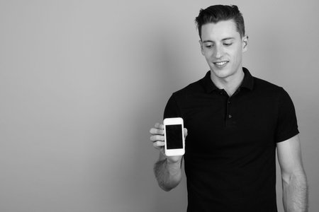 Young handsome man using mobile phone against gray background
