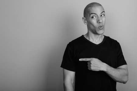 Handsome bald man wearing black shirt against gray backgroundの写真素材