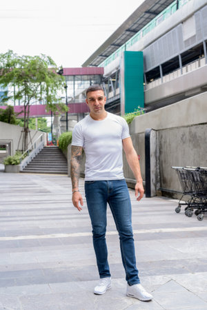 Full body shot of handsome man with tattoos in the city