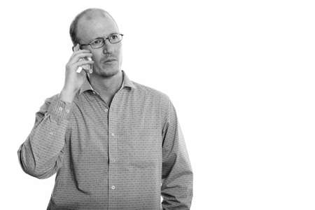 Studio shot of businessman talking on mobile phone while thinkingの写真素材