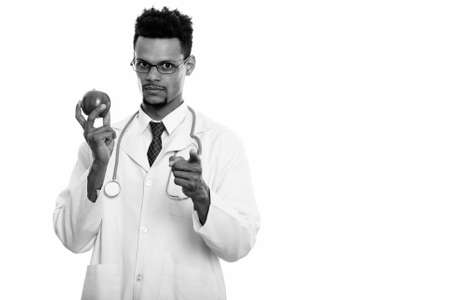 Young African man doctor holding apple while pointing at cameraの写真素材