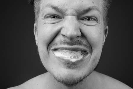 Young handsome man shirtless while grooming against gray backgroundの写真素材