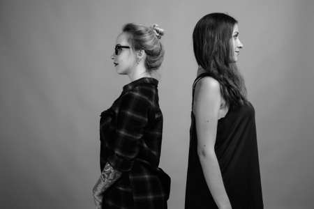 Two young beautiful woman friends against gray backgroundの写真素材