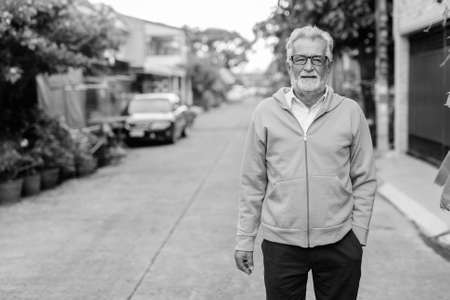 Handsome senior bearded man wearing jacket and eyeglasses outdoorsの写真素材