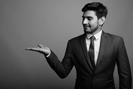 Young handsome bearded Persian businessman against gray backgroundの写真素材
