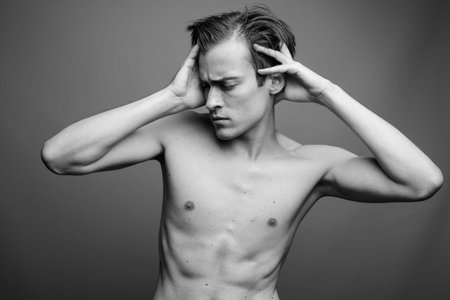 Young handsome man shirtless against gray background