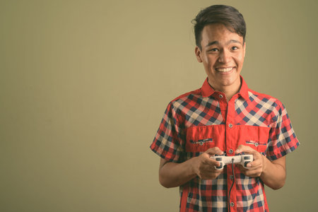 Young handsome Indian man against colored background