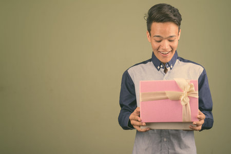 Young handsome Indian man looking smart against colored background