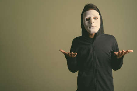 Young handsome Indian man wearing hoodie against colored backgroundの写真素材