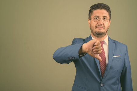 Bearded Persian businessman wearing suit against colored background