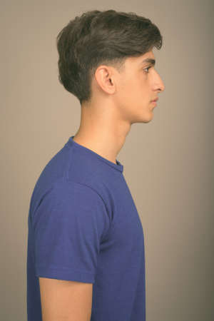 Young handsome Persian teenage boy against gray backgroundの写真素材