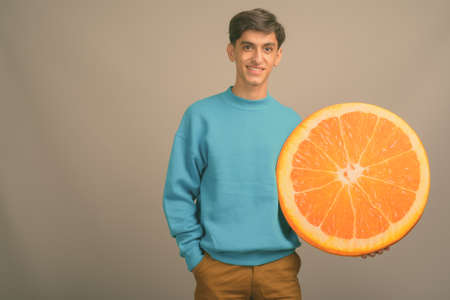 Young handsome Persian teenage boy against gray backgroundの写真素材