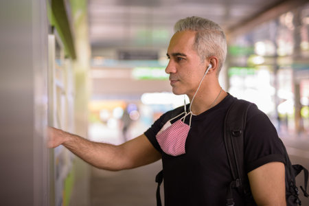 Portrait of Persian man with mask buying ticket at the sky train station