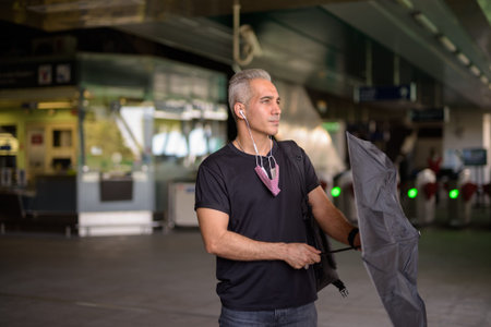 Handsome Persian man opening umbrella at the sky train stationの写真素材