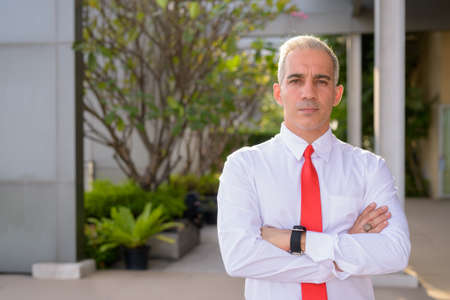Handsome Persian businessman with arms crossed in the city streets outdoorsの写真素材
