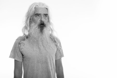 Studio shot of senior bearded man thinking while looking at distance