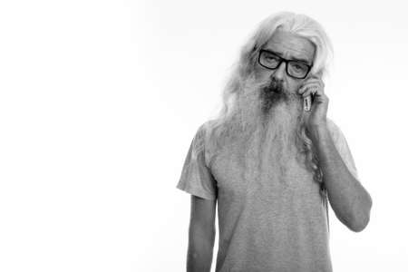 Studio shot of senior bearded man talking on mobile phoneの写真素材